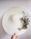 Large white saucer hat with spray of black and white feathers and dimonte motif