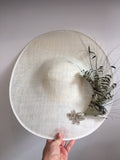 Large white saucer hat with spray of black and white feathers and dimonte motif