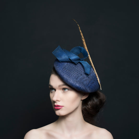 Navy large button beret fascinator/hat with navy trimming and a gold pheasant feather.Rivka Jacobs mllinery