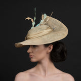 Latte coloured sinamay brimmed hat, with a spray of diamond cut feathers in light orange, coffee, cream. Hand made by Rivka Jacobs Millinery