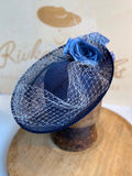 Navy blue saucer hat with light blue flowers and veiling.