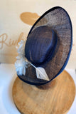 Navy blue percher  mother of the bride hat, with white flowers and arrow feathers. Rivka jacobs millinery. hats Uk