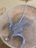 Grey saucer hat with grey feathers, quills and grey arrow feathers